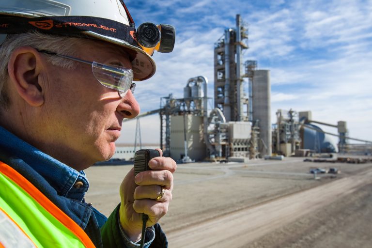 A man in a hard hat is talking on a radio during an industrial photography shoot at a cement plant.