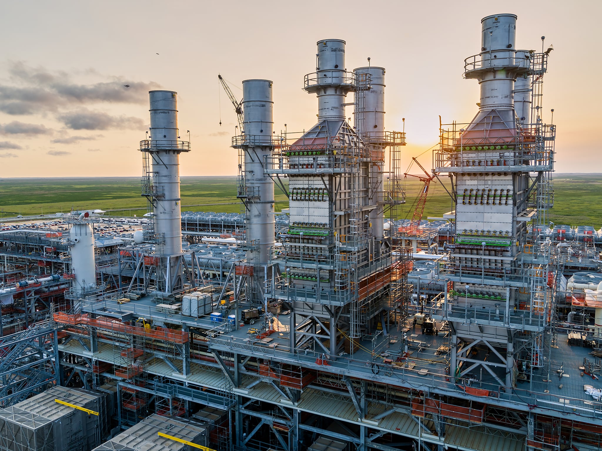 A corporate photograph showcasing an aerial view of an LNG facility at sunset.
